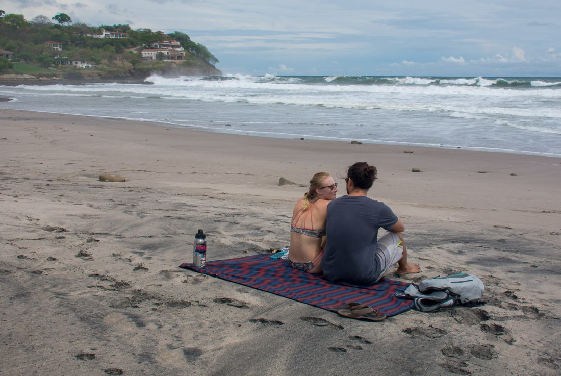 Picture of two people sitting on the Kachula Adventure blanket at playa santana in Nicaragua. 