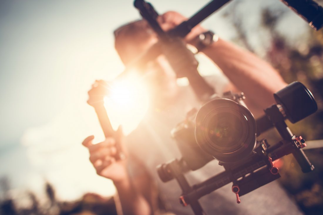 Picture of a camera on a gimbal with a sun flare from behind the camera man. 